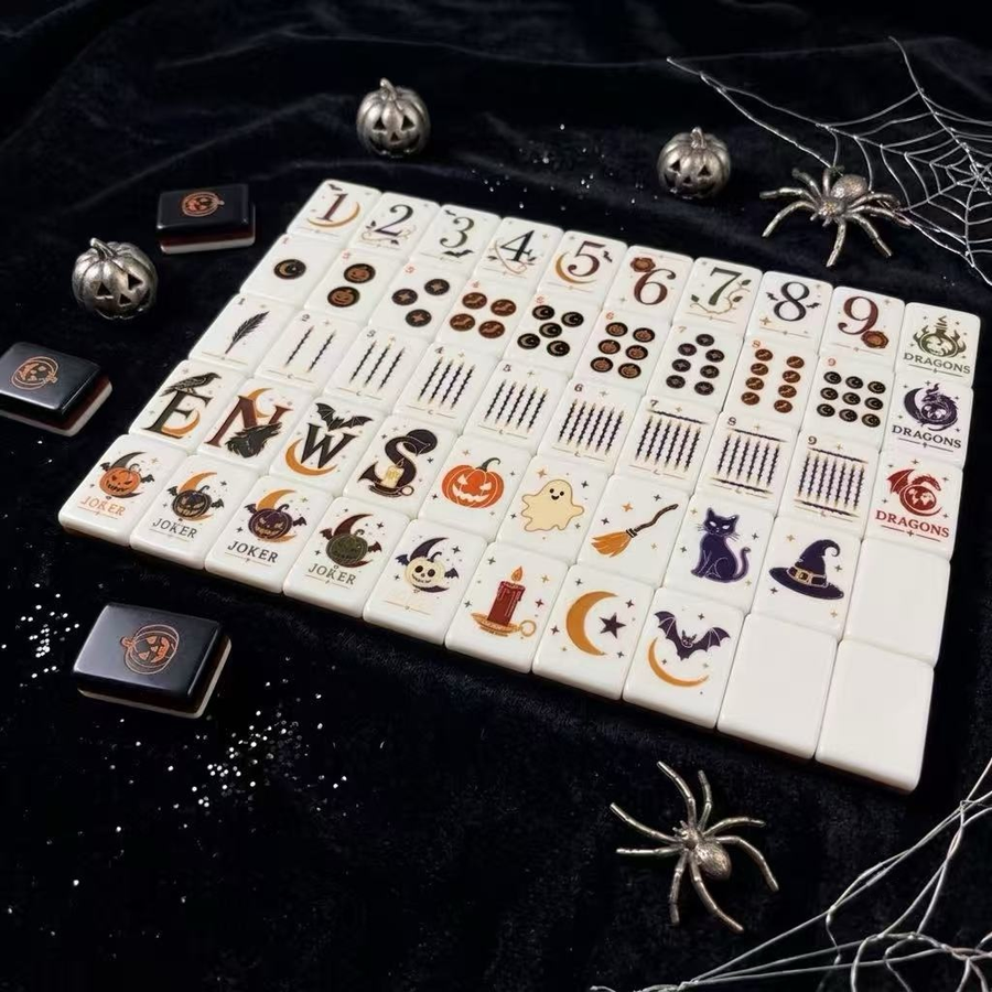 Hallows' Eve mahjong tiles arranged on black fabric with pumpkins and spiderweb decorations